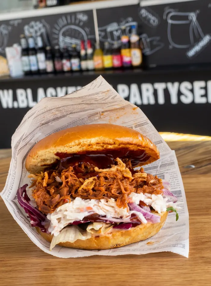 Pulled Pork Sandwich mit Coleslaw, Salat, Röstzwiebeln und BBQ Sauce